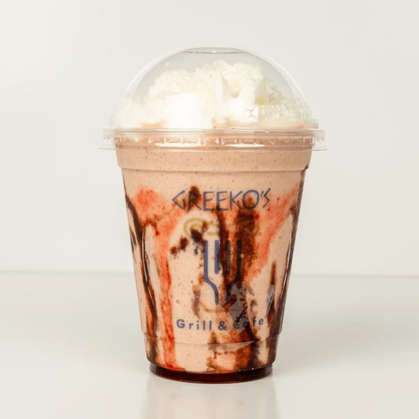 A Greekos Grill & Cafe frappe with whipped cream, chocolate, and strawberry drizzle in a plastic cup.