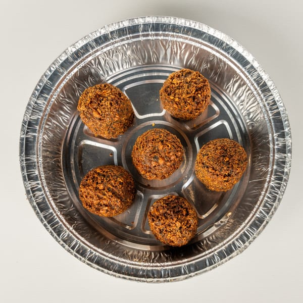 Six crispy falafel balls in a round, silver foil takeout container from Greekos Grill & Cafe.