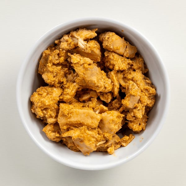 Close-up overhead view of a white bowl filled with Greekos Grill & Cafe's seasoned chicken pieces.