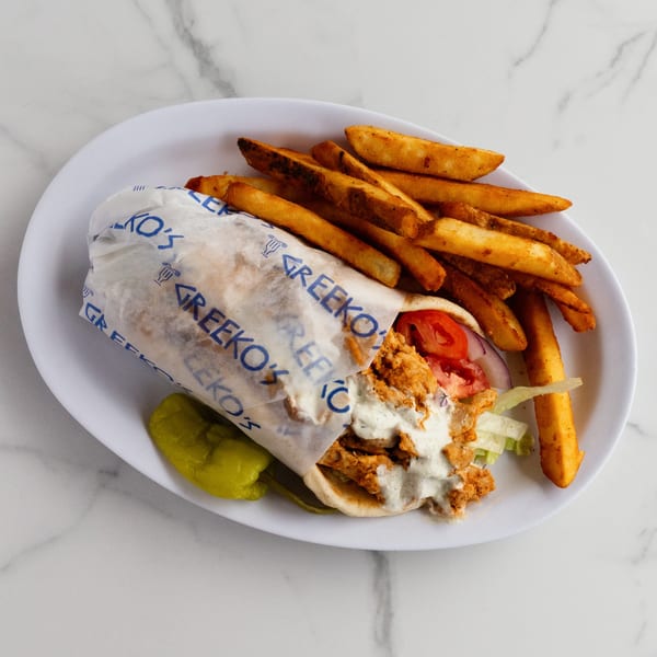 Greekko's chicken gyro with tzatziki sauce, tomatoes, lettuce, and a side of fries and a pepper.