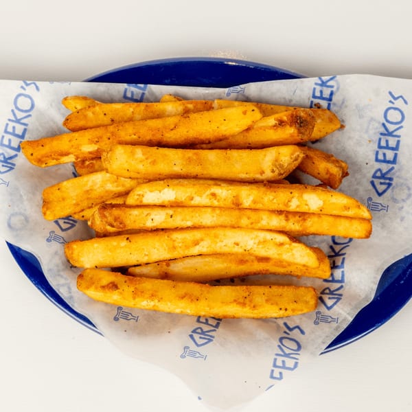 Golden-brown Greekos Grill & Cafe fries, seasoned with spices, served on branded paper in a blue basket.